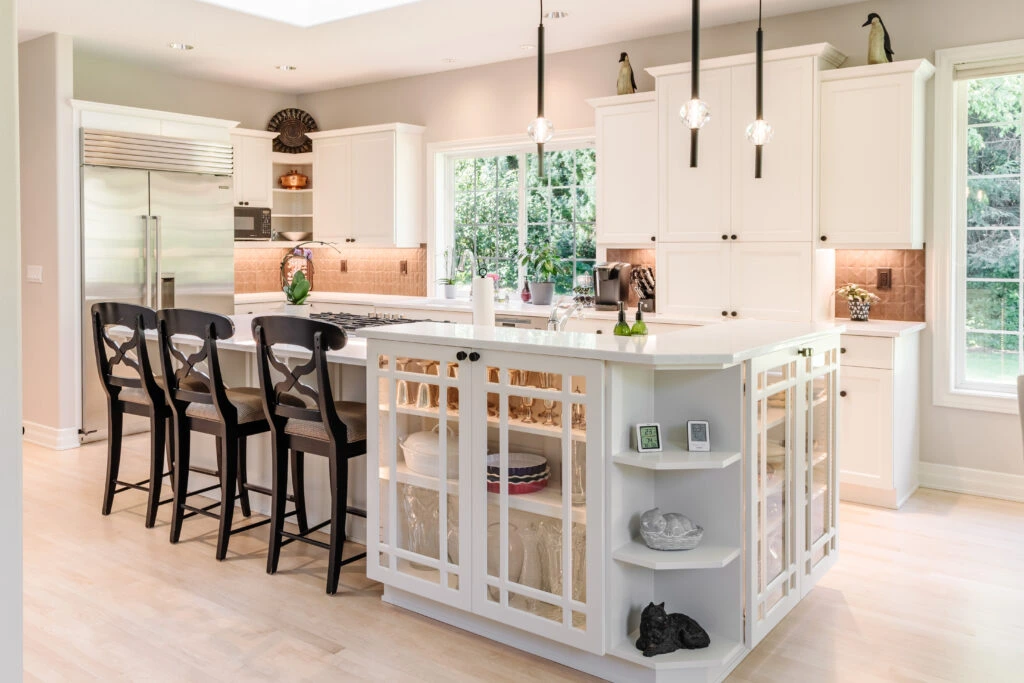 Elegant white kitchen featuring a multi-level island with display cabinetry and curved shelving, built by Black Cat Design Build LLC.