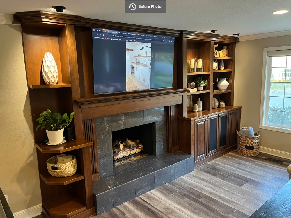 Living room with dated wood cabinetry, dark tile fireplace surround, and television shown before its renovation by Black Cat Design Build LLC.