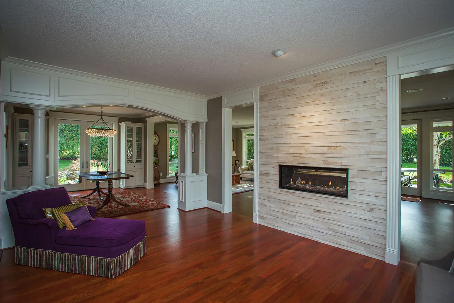 Open-concept living space with a stacked stone fireplace and arched entryway built by Black Cat Design Build LLC.