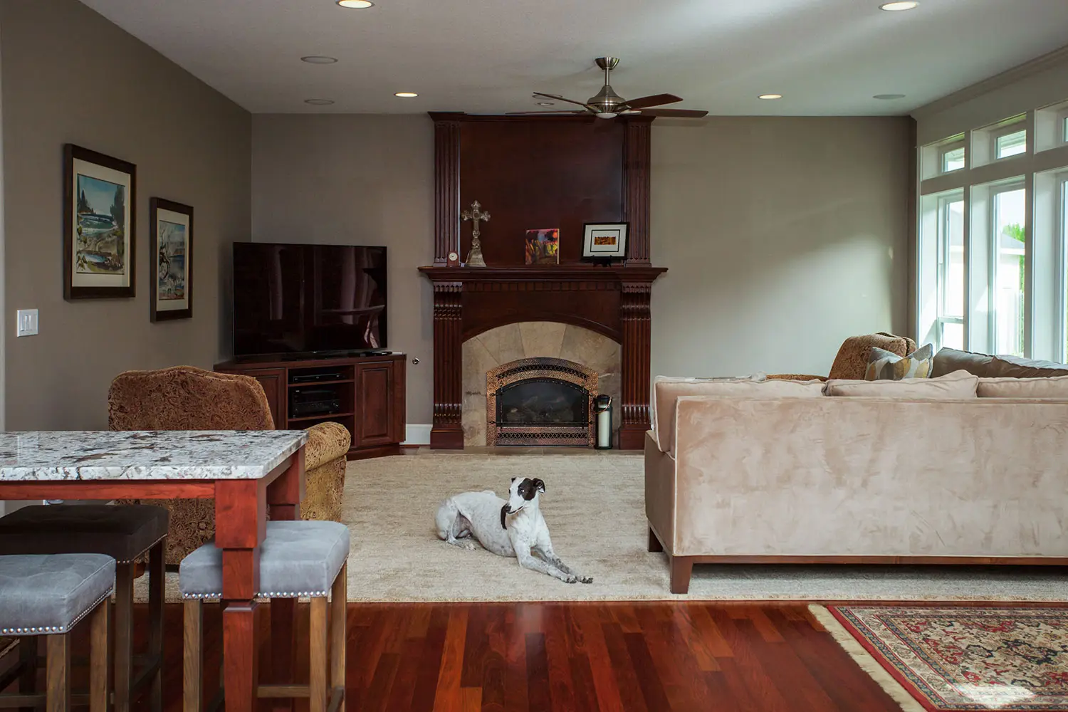Comfortable family room with a fireplace, media console, hardwood floors, and a dog relaxing on the area rug.