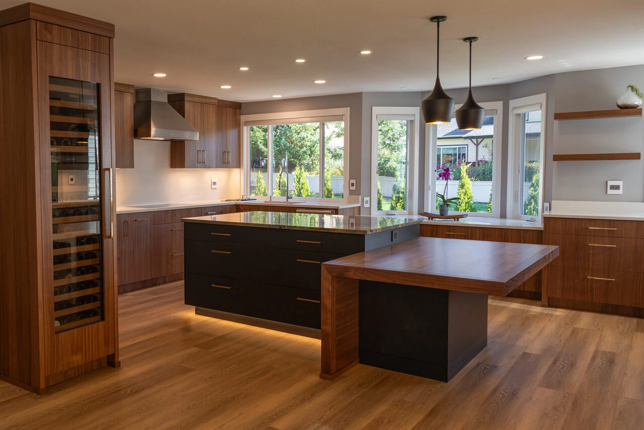 Contemporary kitchen with wood-grain cabinets, a dark waterfall island, pendant lighting, and a tall built-in wine refrigerator.