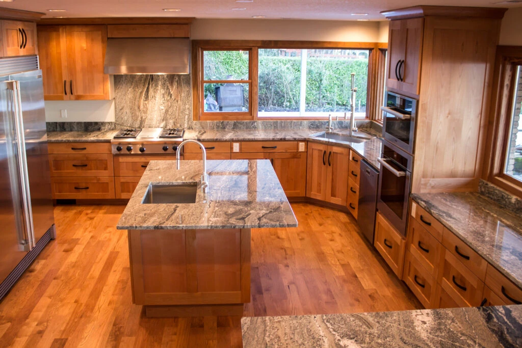Spacious kitchen with natural wood cabinets, granite countertops, a large center island, and a stainless steel professional range.