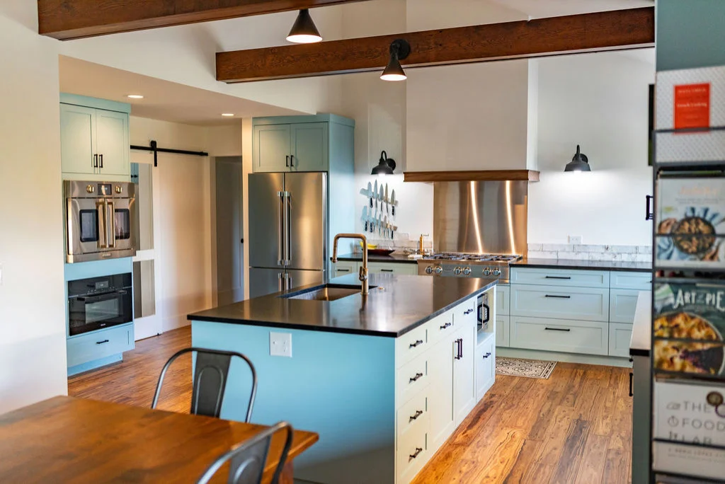 Stylish kitchen interior with contrasting cabinetry, vaulted ceiling, and rustic architectural details.