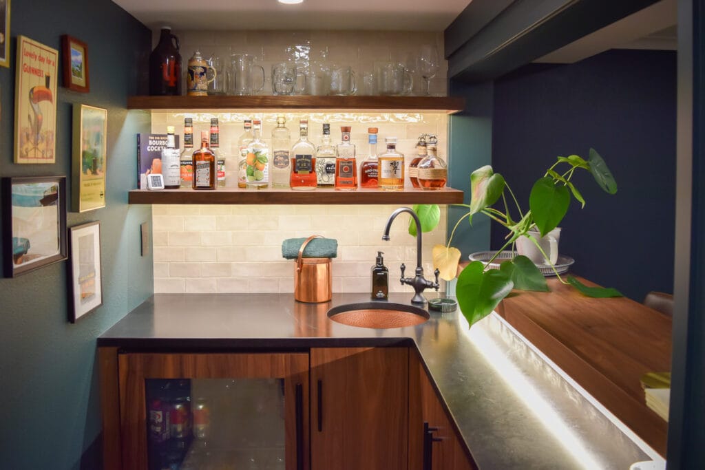 High-end bar detail showing a hand-hammered copper sink, soapstone counters, and a classic small-scale white subway tile backsplash.